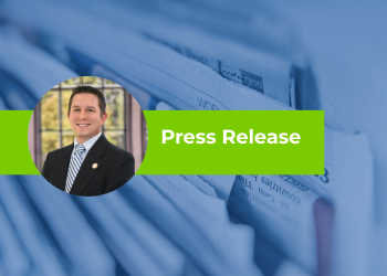A close-up stack of newspapers in the background with a bright green banner reading “Press Release,” and a circular inset image showing an individual dressed in professional attire.